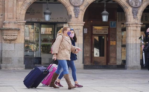 Dos turistas pasean por la Plaza Mayor de Salamanca con sus maletas. /S. H.